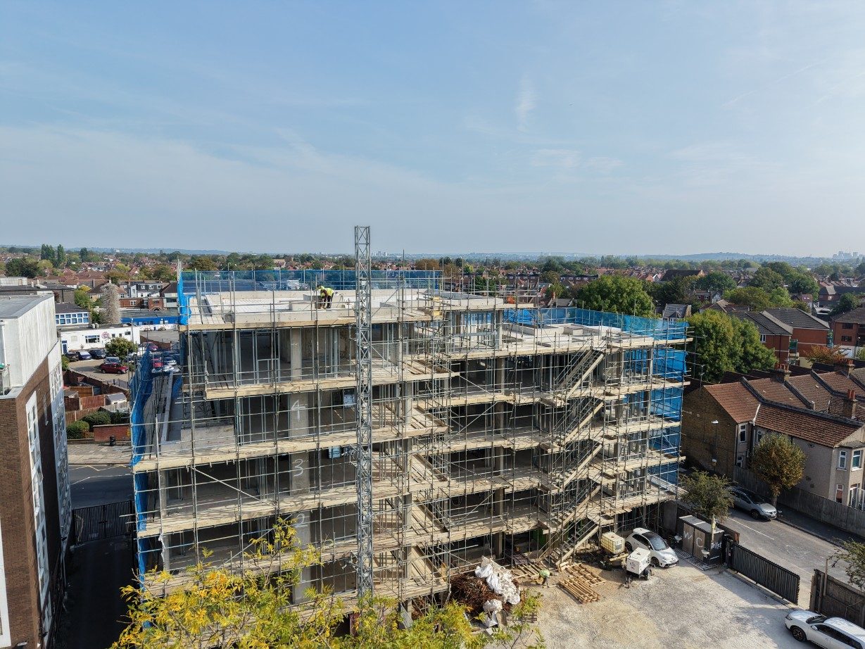 Rear elevation of the development under scaffold, with the service yard and terraced houses behind